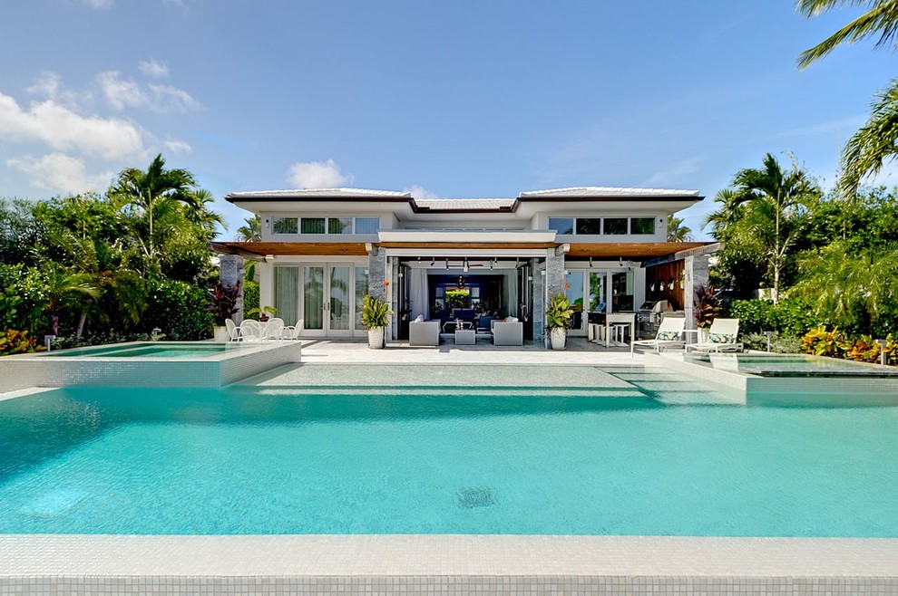 Photo of a large contemporary backyard rectangular pool in Miami with a hot tub.