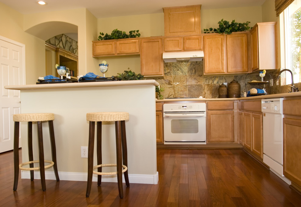Eat-in kitchen - large medium tone wood floor eat-in kitchen idea in Minneapolis with light wood cabinets, multicolored backsplash, stone tile backsplash, white appliances and an island