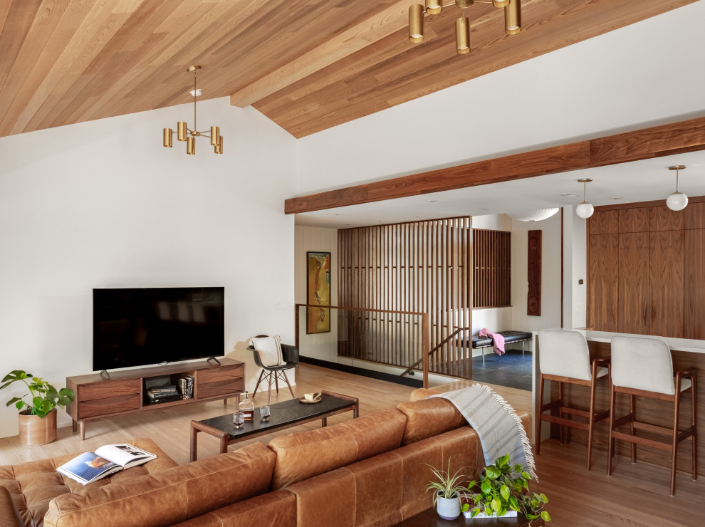 Immagine di un soggiorno moderno con parquet chiaro, camino classico, cornice del camino in pietra, TV autoportante e soffitto in legno