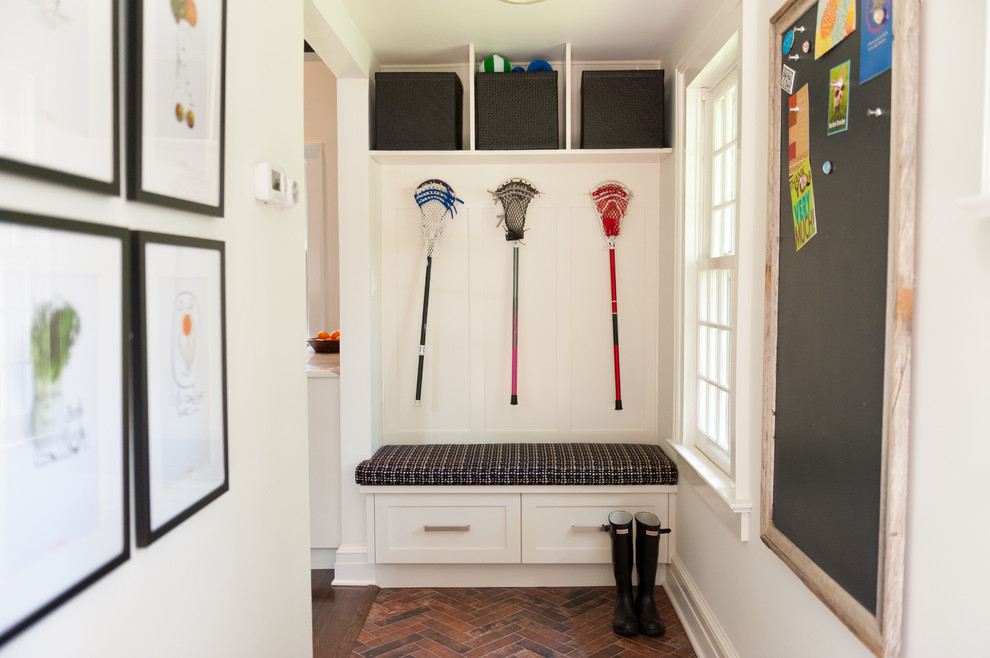 Photo of a small transitional mudroom in New York with white walls and brick floors.