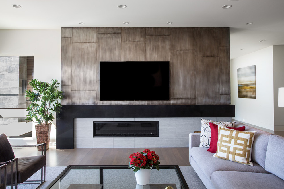 Inspiration for a mid-sized contemporary open concept living room in Salt Lake City with a ribbon fireplace, a home bar, white walls, light hardwood floors, a tile fireplace surround, a wall-mounted tv and grey floor.
