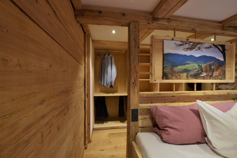 Mittelgroßes Rustikales Hauptschlafzimmer mit weißer Wandfarbe, dunklem Holzboden, freigelegten Dachbalken und Holzdielenwänden in Sonstige