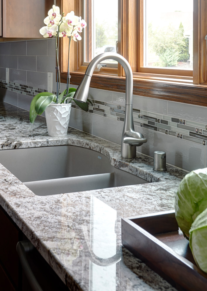 Inspiration for a large transitional l-shaped dark wood floor enclosed kitchen remodel in Milwaukee with a drop-in sink, shaker cabinets, medium tone wood cabinets, granite countertops, white backsplash, porcelain backsplash, stainless steel appliances and an island