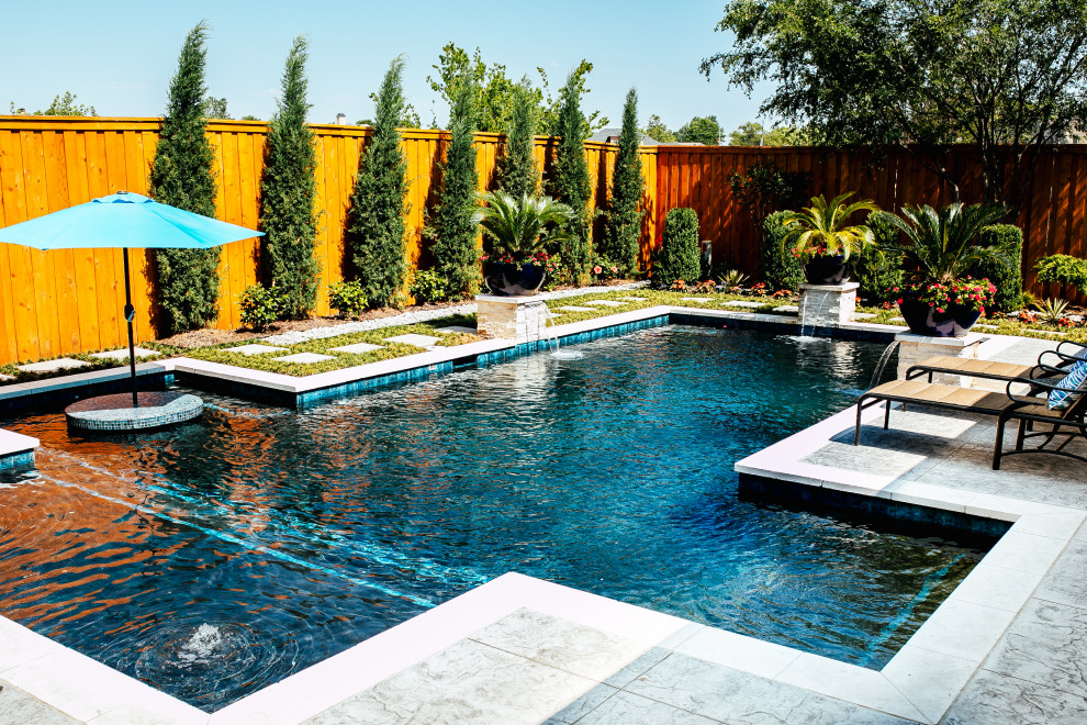 Modelo de piscina con fuente alargada actual grande rectangular en patio trasero con losas de hormigón