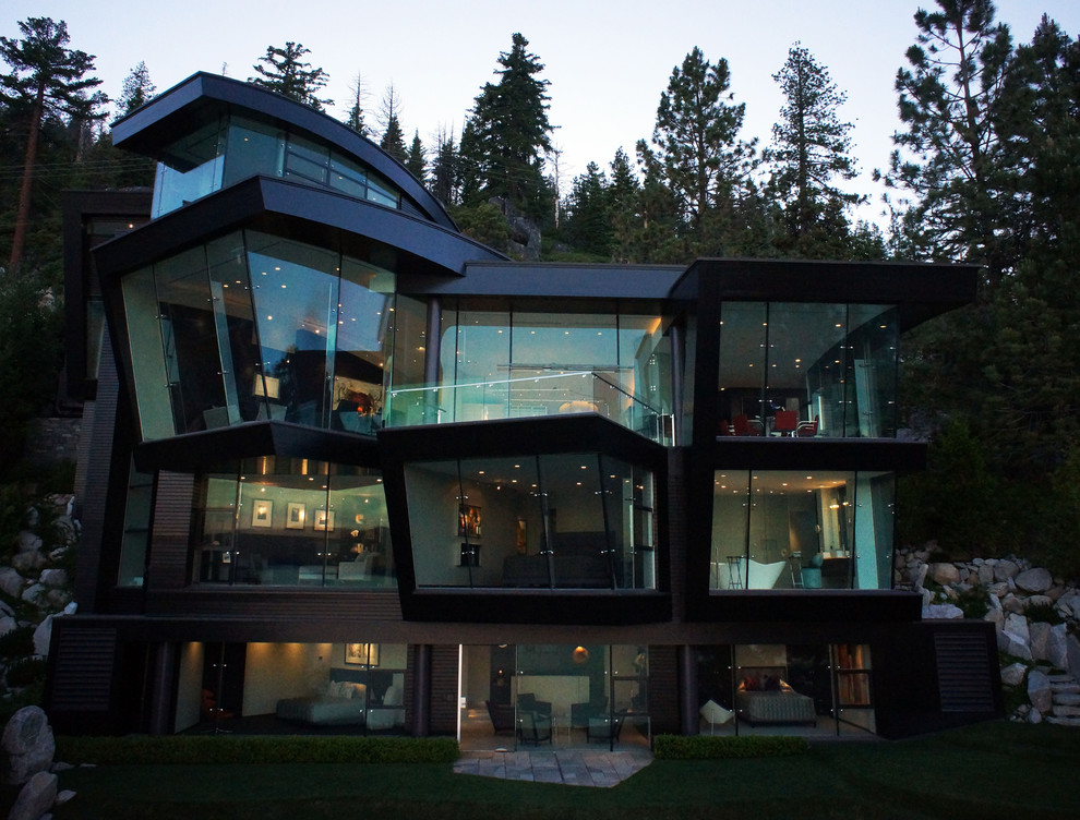 This is an example of a large contemporary three-storey glass house exterior in Other with a flat roof and a metal roof.