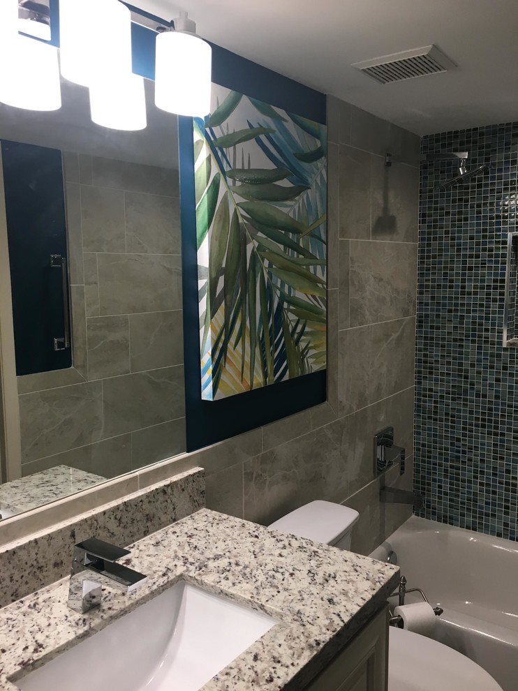 This is an example of a mid-sized tropical 3/4 bathroom in Boston with raised-panel cabinets, white cabinets, a two-piece toilet, blue walls, an undermount sink, granite benchtops, an alcove tub, a shower/bathtub combo, blue tile, mosaic tile, cement tiles, beige floor, a shower curtain and white benchtops.