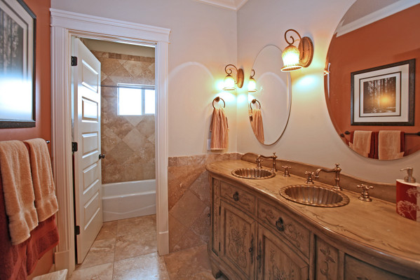 Inspiration for a large traditional 3/4 bathroom in Salt Lake City with a drop-in sink, furniture-like cabinets, wood benchtops, a freestanding tub, a shower/bathtub combo, beige tile, stone tile, beige walls, travertine floors and light wood cabinets.