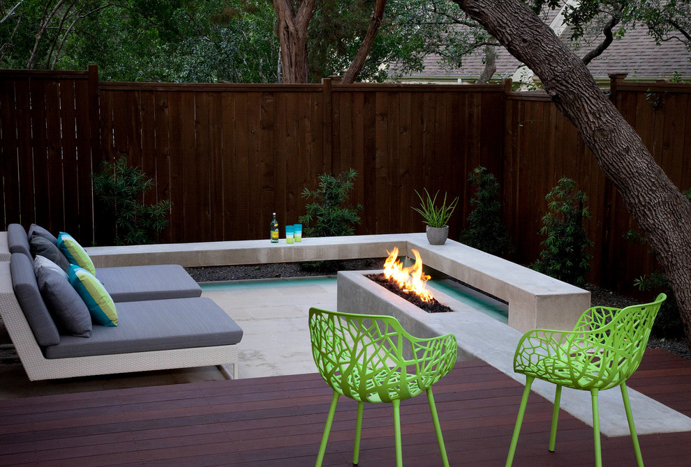 Photo of a mid-sized contemporary backyard deck in Austin with a fire feature and a roof extension.