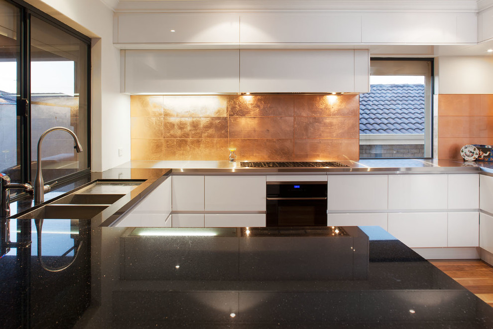 Mid-sized contemporary l-shaped eat-in kitchen in Perth with an undermount sink, white cabinets, granite benchtops, metallic splashback, glass tile splashback, stainless steel appliances, medium hardwood floors and with island.