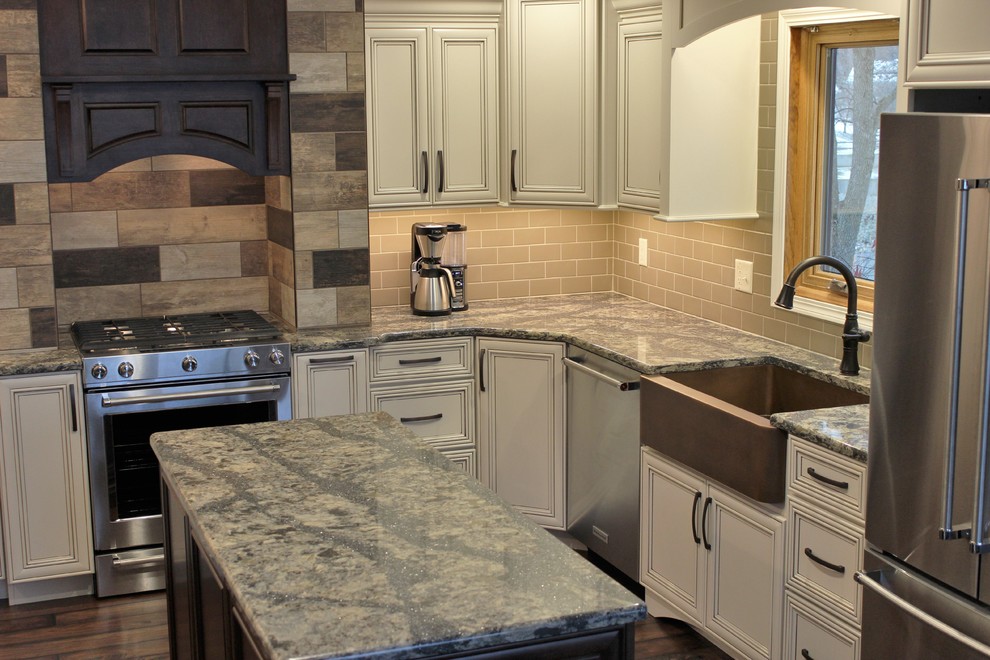 Photo of a large traditional u-shaped eat-in kitchen in Chicago with a farmhouse sink, flat-panel cabinets, beige cabinets, quartz benchtops, brown splashback, ceramic splashback, stainless steel appliances, vinyl floors and with island.