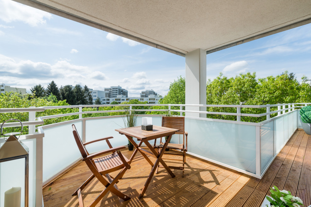 Photo of a mid-sized contemporary balcony in Munich with a roof extension and mixed railing.