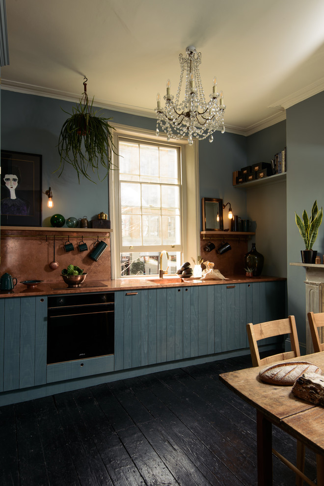 This is an example of a mid-sized modern eat-in kitchen in Other with an integrated sink, flat-panel cabinets, blue cabinets, copper benchtops, orange splashback, panelled appliances, painted wood floors, no island and black floor.