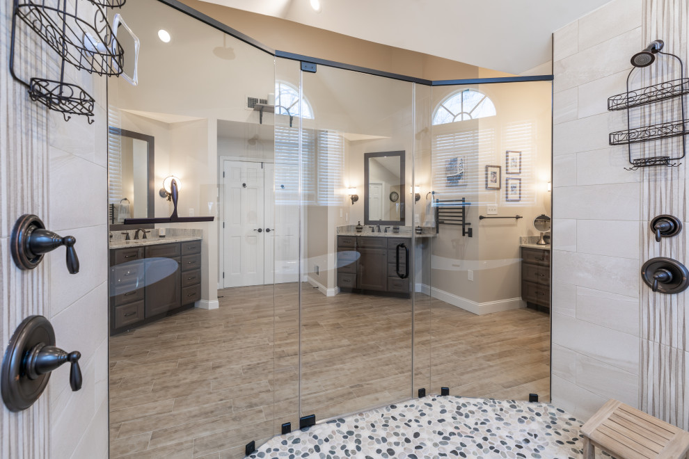 Photo of a large contemporary ensuite bathroom in DC Metro with brown cabinets, a freestanding bath, a shower/bath combination, a one-piece toilet, grey tiles, beige walls, porcelain flooring, a submerged sink, brown floors, a hinged door, grey worktops, an enclosed toilet, double sinks and a built in vanity unit.