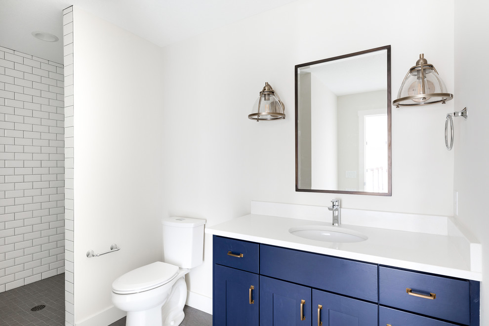 Design ideas for a mid-sized transitional kids wet room bathroom in Minneapolis with shaker cabinets, blue cabinets, an undermount sink, quartzite benchtops, a hinged shower door, white benchtops, white tile, subway tile, white walls, ceramic floors, grey floor and a two-piece toilet.