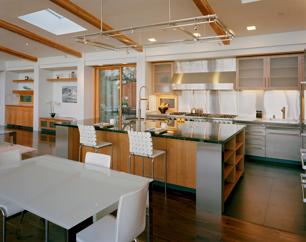 Inspiration for a mid-sized contemporary l-shaped eat-in kitchen in San Francisco with a double-bowl sink, flat-panel cabinets, medium wood cabinets, granite benchtops, metallic splashback, metal splashback, stainless steel appliances, dark hardwood floors, with island, brown floor, black benchtop and exposed beam.