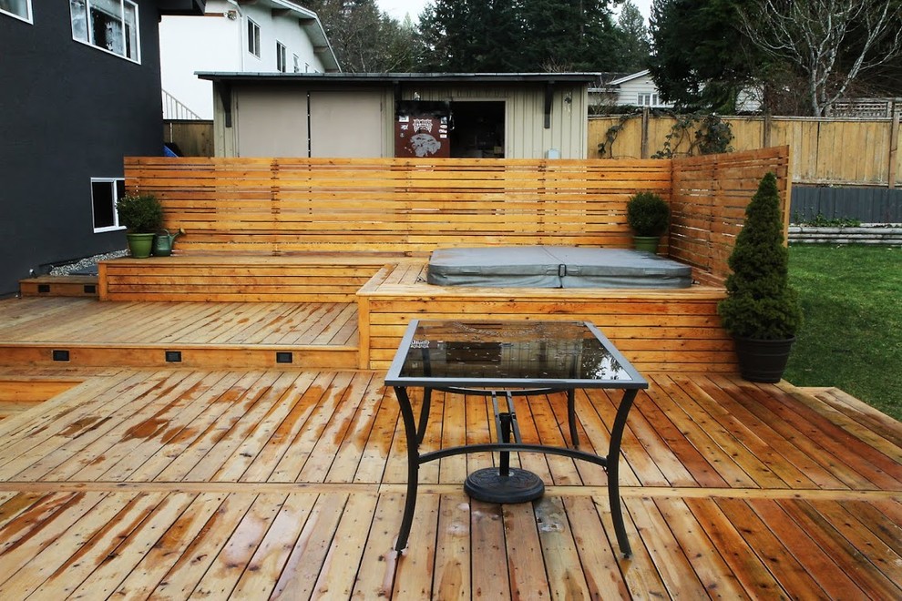 This is an example of a large country backyard deck in Vancouver with a water feature and no cover.
