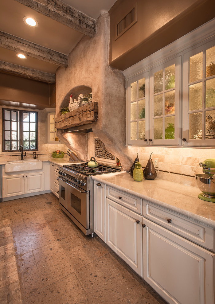 Large mountain style l-shaped travertine floor open concept kitchen photo in Phoenix with a farmhouse sink, raised-panel cabinets, white cabinets, granite countertops, beige backsplash, stone tile backsplash, stainless steel appliances and an island