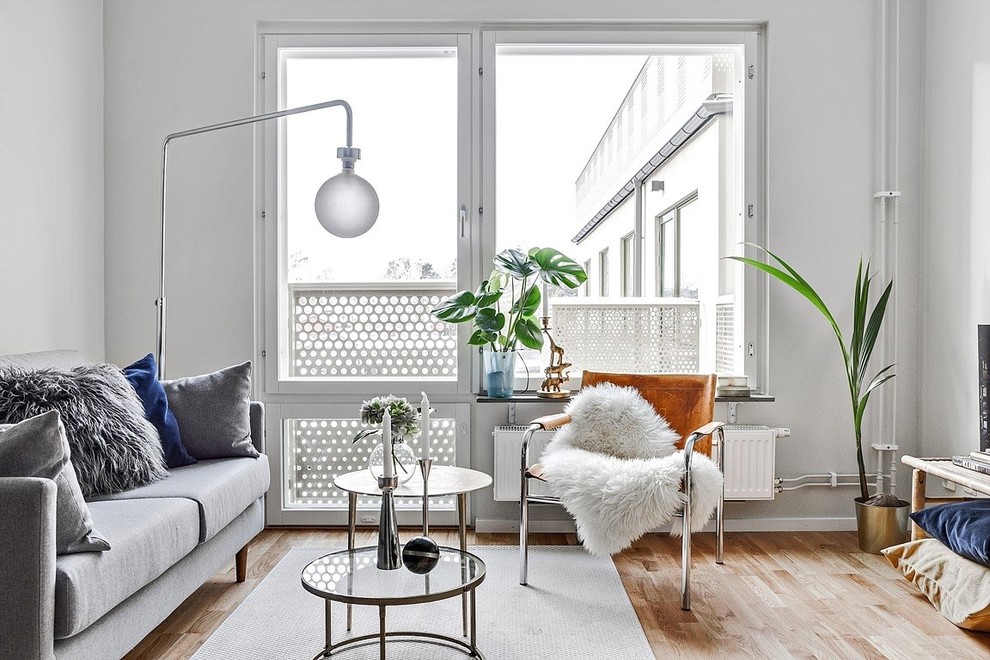 This is an example of a small scandinavian formal enclosed living room in Stockholm with white walls, light hardwood floors and beige floor.