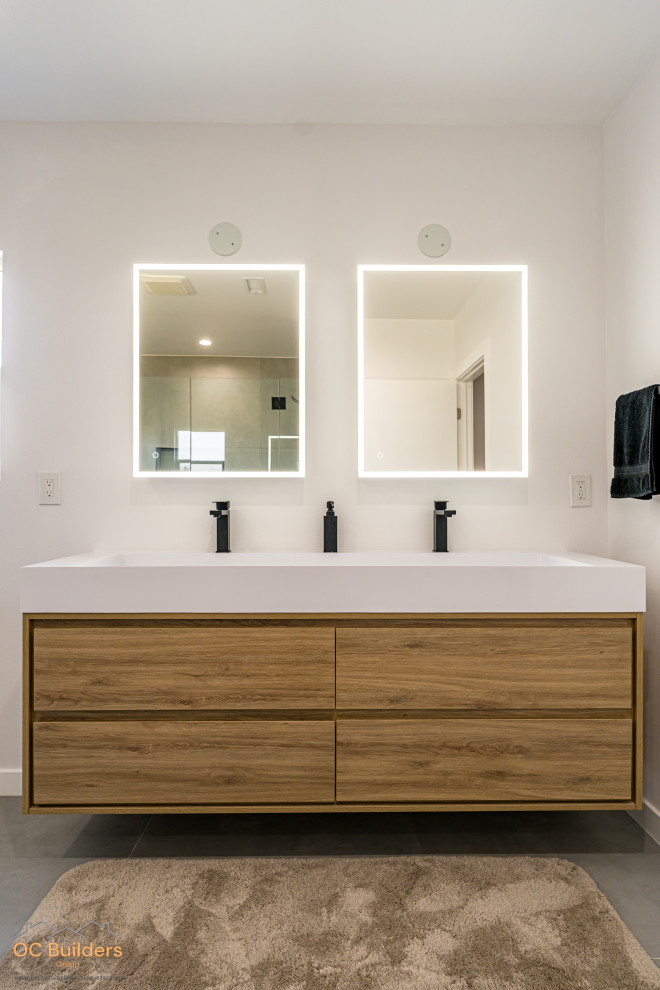 Inspiration for a medium sized modern ensuite bathroom in Orange County with flat-panel cabinets, beige cabinets, an alcove bath, an alcove shower, a one-piece toilet, white tiles, ceramic tiles, white walls, ceramic flooring, a submerged sink, laminate worktops, brown floors, a hinged door, white worktops, a wall niche, double sinks, a floating vanity unit, a vaulted ceiling and panelled walls.