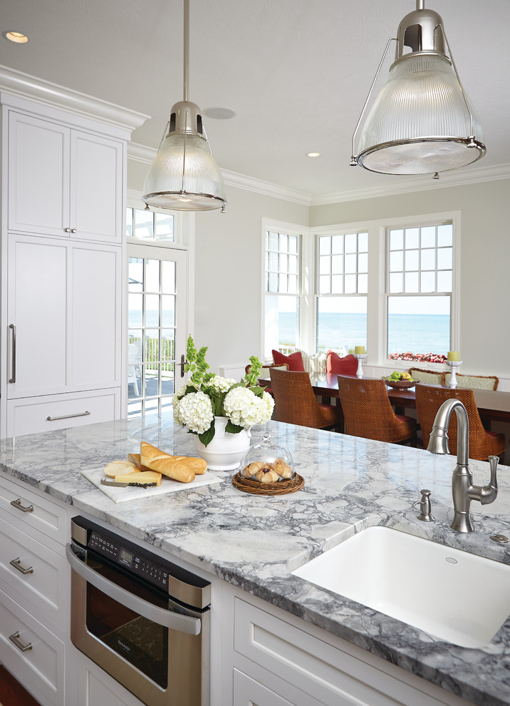Photo of a beach style eat-in kitchen in Grand Rapids with a farmhouse sink, white splashback, ceramic splashback, stainless steel appliances and with island.