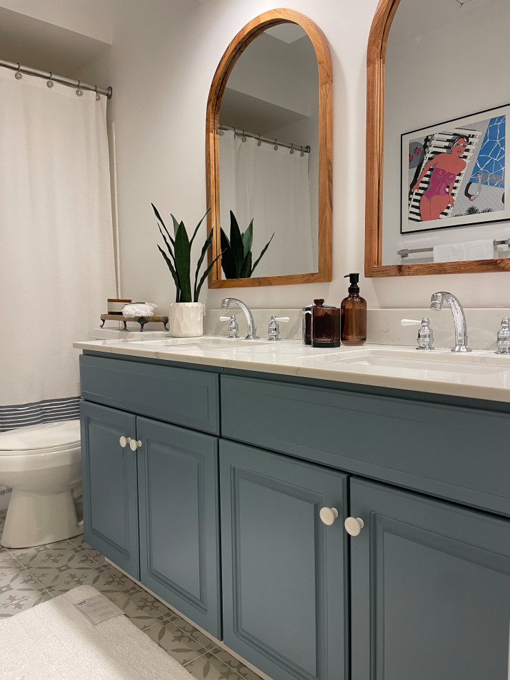 Photo of a mid-sized mediterranean kids bathroom in Baltimore with raised-panel cabinets, blue cabinets, a shower/bathtub combo, gray tile, ceramic floors, an undermount sink, marble benchtops, grey floor, a shower curtain, white benchtops, a double vanity and a built-in vanity.