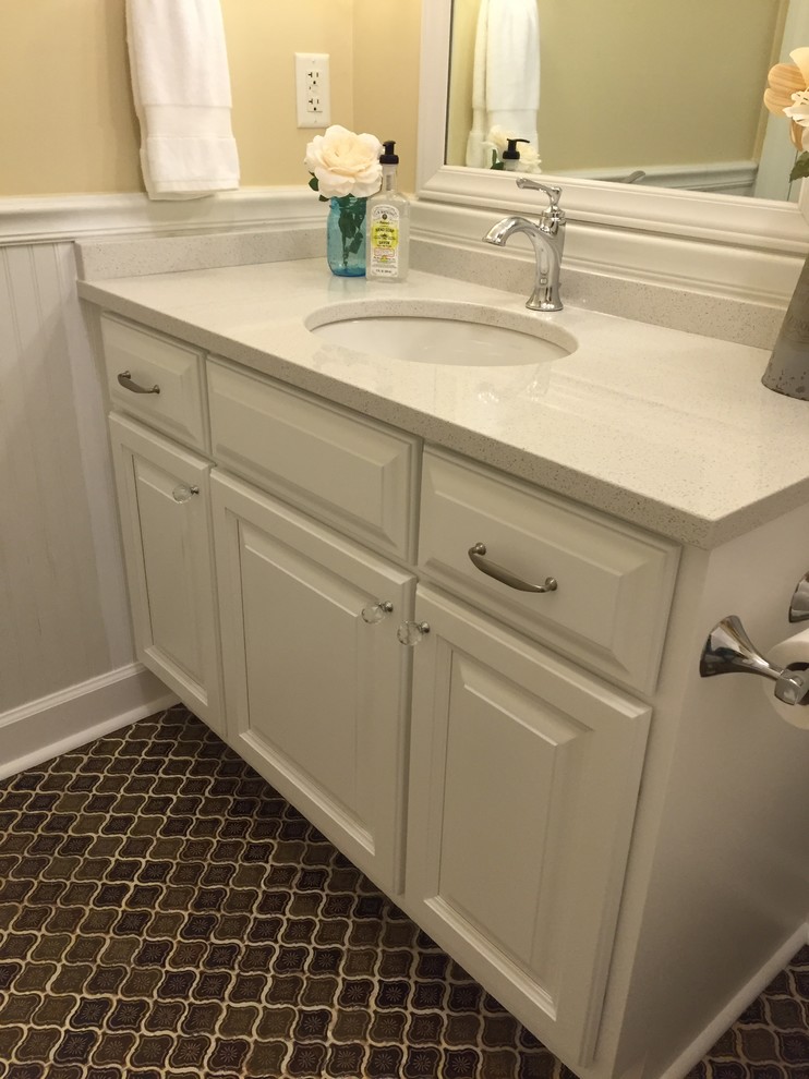 This is an example of a mid-sized country bathroom in Charleston with an undermount sink, raised-panel cabinets, white cabinets, quartzite benchtops, a shower/bathtub combo, brown tile, ceramic tile, yellow walls and ceramic floors.