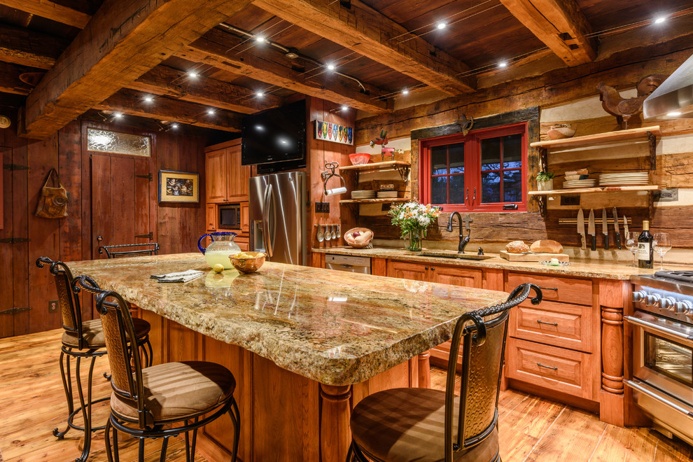 Photo of a country kitchen in Austin with an undermount sink, raised-panel cabinets, medium wood cabinets, timber splashback, stainless steel appliances, medium hardwood floors and with island.