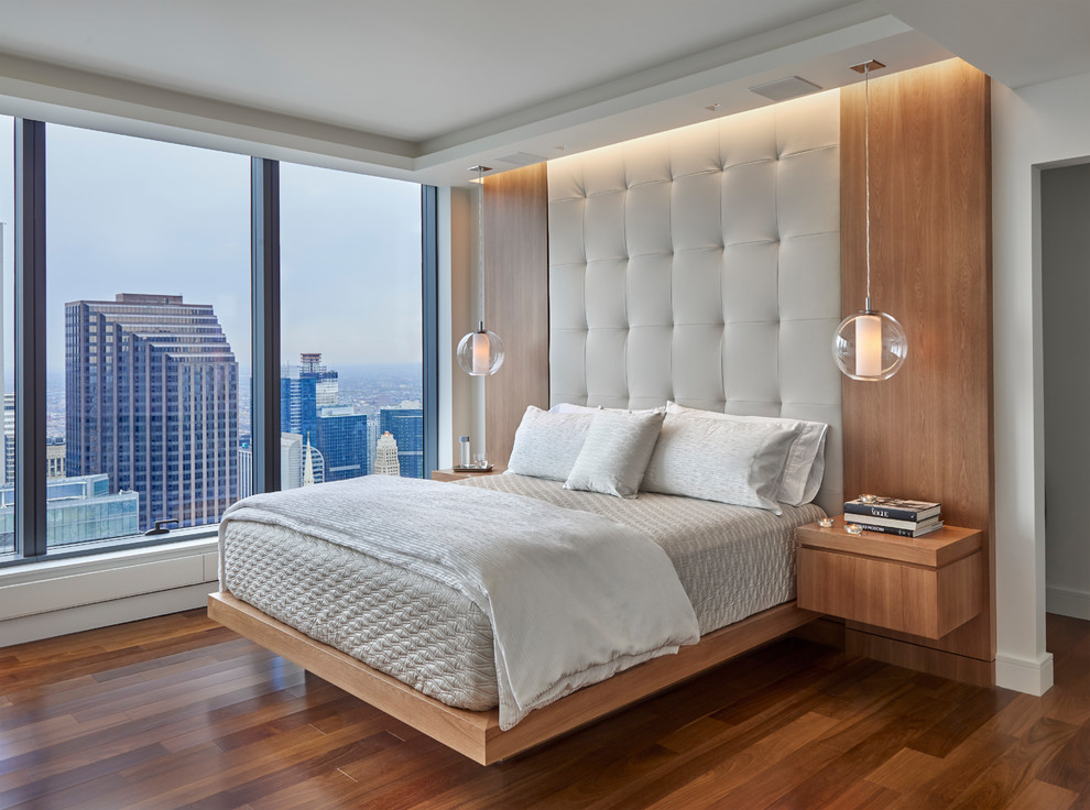 Design ideas for a contemporary bedroom in Chicago with white walls, medium hardwood floors and brown floor.