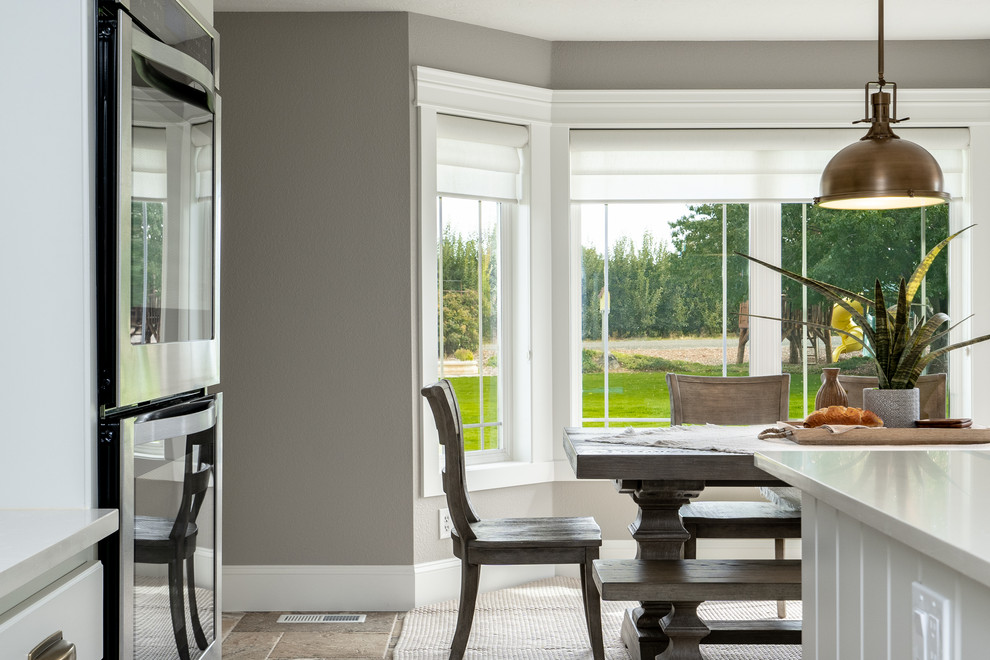 Example of a transitional u-shaped travertine floor and brown floor open concept kitchen design in Seattle with an undermount sink, raised-panel cabinets, white cabinets, quartz countertops, white backsplash, porcelain backsplash, stainless steel appliances, an island and white countertops