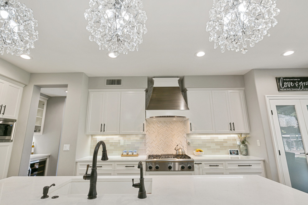 Inspiration for a huge transitional u-shaped travertine floor and beige floor open concept kitchen remodel in Orange County with a single-bowl sink, shaker cabinets, white cabinets, quartz countertops, multicolored backsplash, stone tile backsplash, stainless steel appliances, an island and white countertops