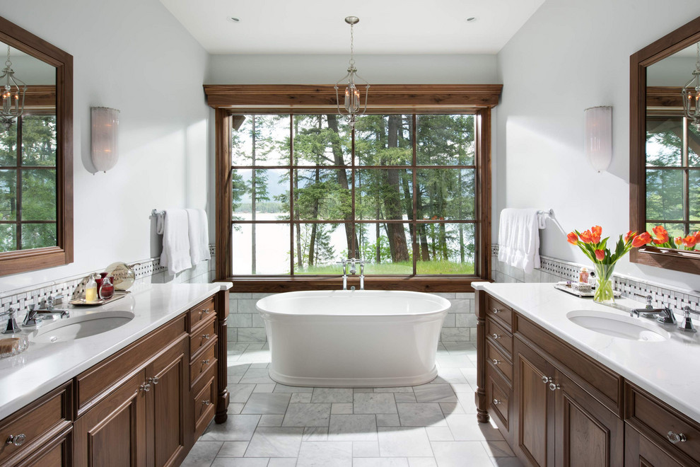 Inspiration for a rustic master gray tile and subway tile gray floor and double-sink freestanding bathtub remodel with recessed-panel cabinets, dark wood cabinets, gray walls, an undermount sink, white countertops and a freestanding vanity