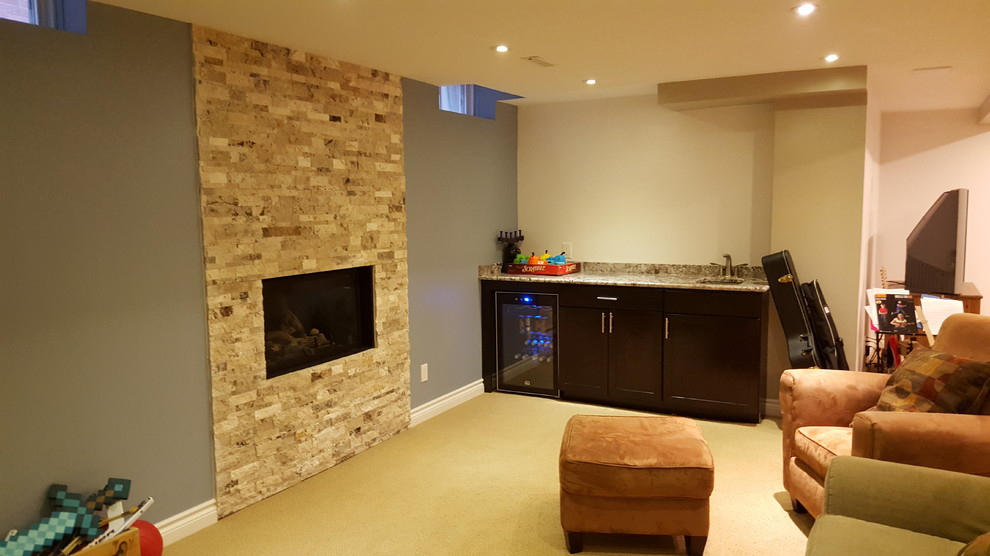 Photo of a mid-sized traditional fully buried basement in Toronto with beige walls, carpet, a standard fireplace and a stone fireplace surround.