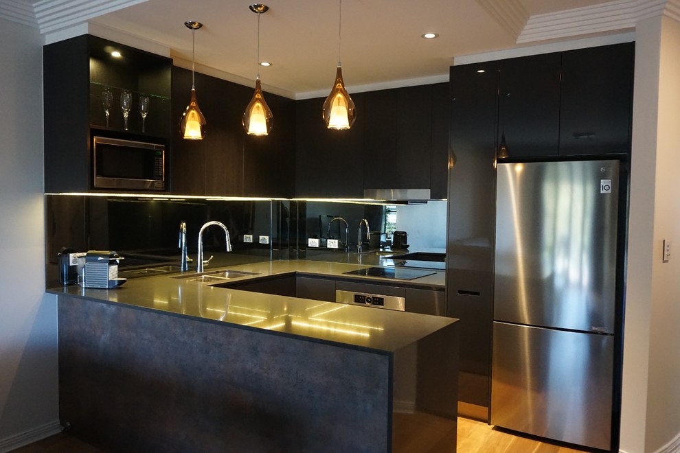 Design ideas for a mid-sized contemporary u-shaped eat-in kitchen in Sydney with an undermount sink, flat-panel cabinets, dark wood cabinets, quartz benchtops, metallic splashback, mirror splashback, stainless steel appliances, light hardwood floors and a peninsula.