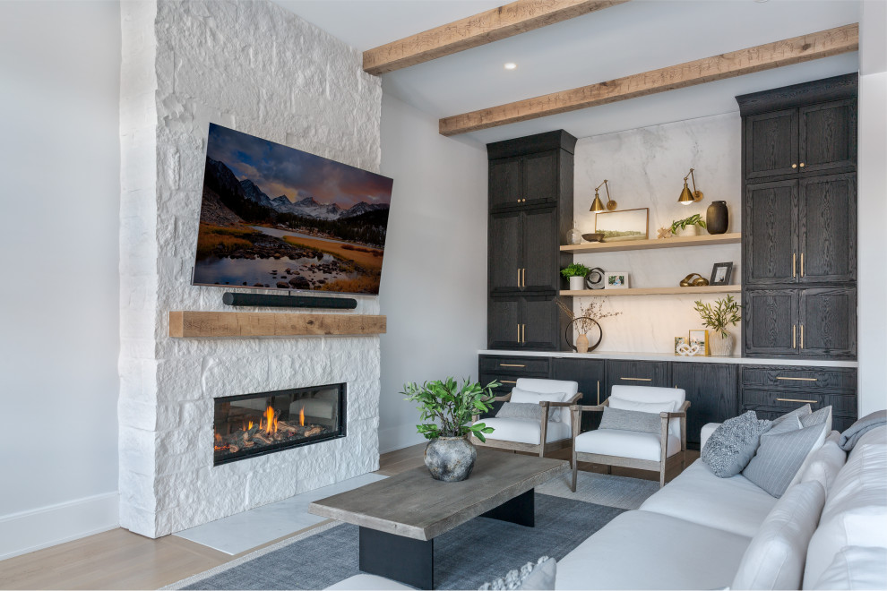Cette image montre une salle de séjour traditionnelle avec un mur blanc, parquet clair, une cheminée standard, un manteau de cheminée en pierre, un sol beige et poutres apparentes.