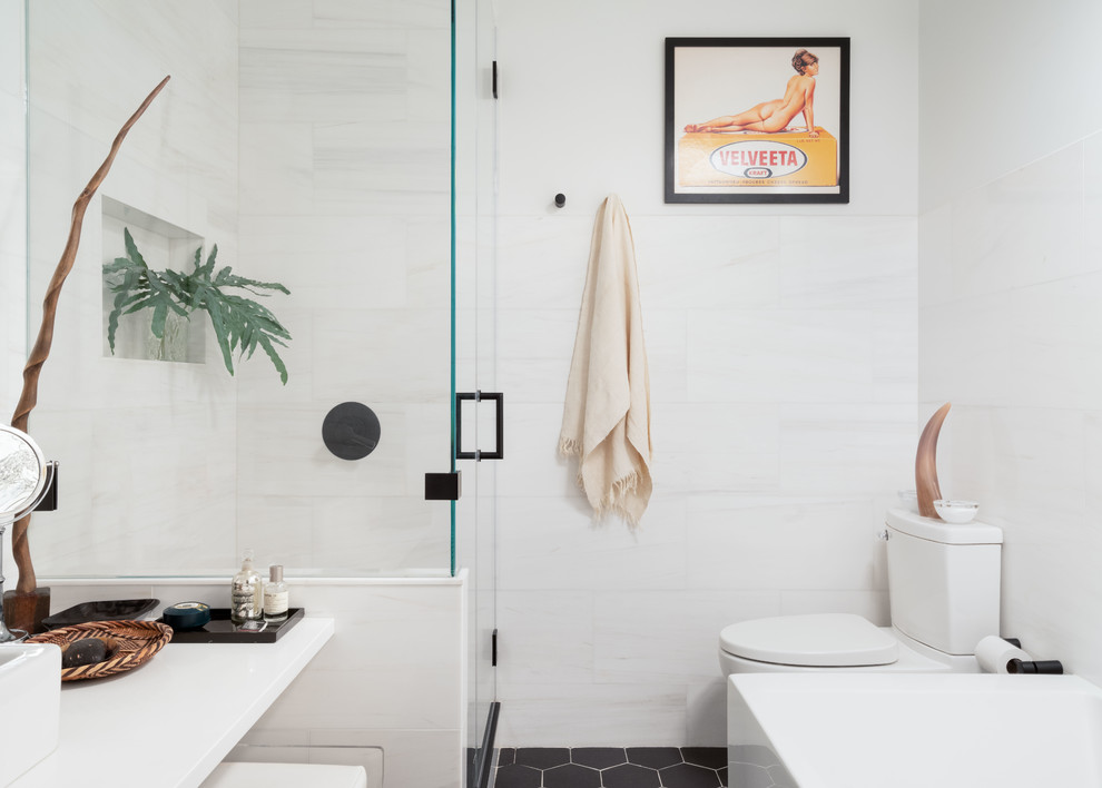 Small eclectic master bathroom in New York with white cabinets, a freestanding tub, a corner shower, a one-piece toilet, white tile, marble, white walls, ceramic floors, a vessel sink, granite benchtops, black floor, a hinged shower door and white benchtops.