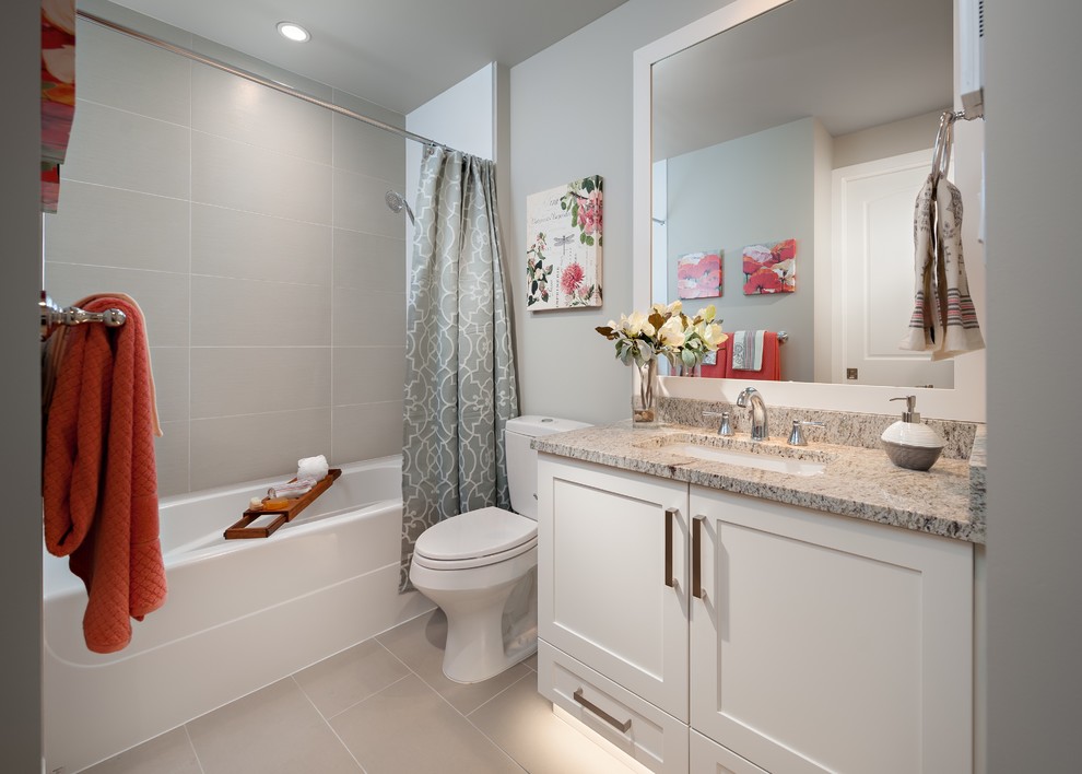 Inspiration for a mid-sized transitional 3/4 bathroom in Vancouver with shaker cabinets, white cabinets, an alcove tub, a shower/bathtub combo, a two-piece toilet, gray tile, porcelain tile, grey walls, porcelain floors, an undermount sink, granite benchtops, grey floor and a shower curtain.