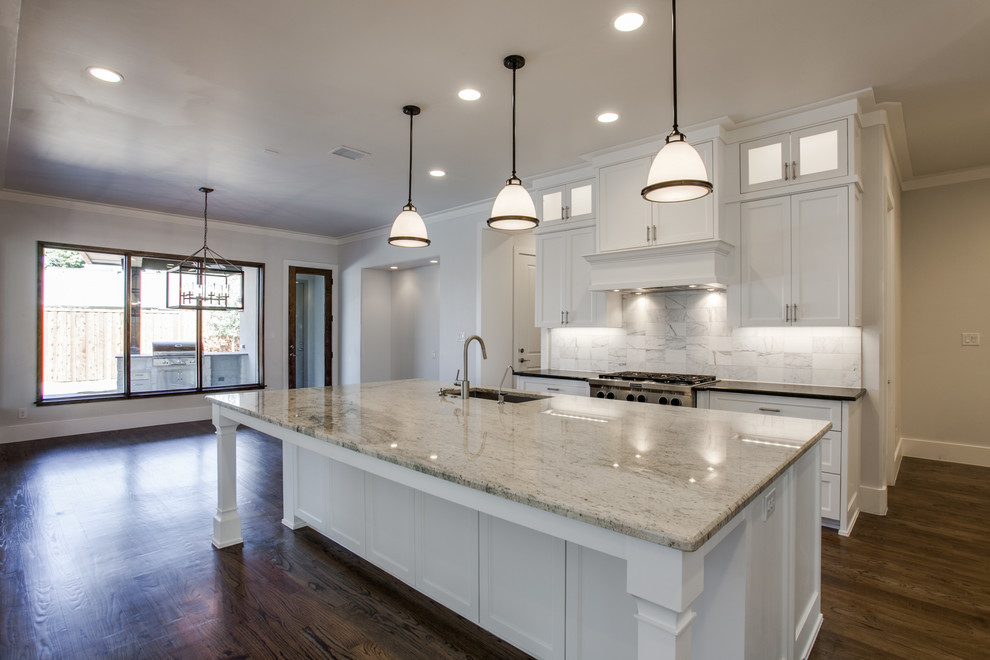 Inspiration for a large transitional galley medium tone wood floor eat-in kitchen remodel in Dallas with an undermount sink, shaker cabinets, white cabinets, granite countertops, white backsplash, marble backsplash, stainless steel appliances and an island