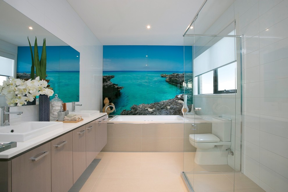 This is an example of a mid-sized beach style master bathroom in Melbourne with a drop-in sink, flat-panel cabinets, light wood cabinets, engineered quartz benchtops, a drop-in tub, a corner shower, a two-piece toilet, beige tile, porcelain tile, white walls, porcelain floors, beige floor, a hinged shower door and white benchtops.