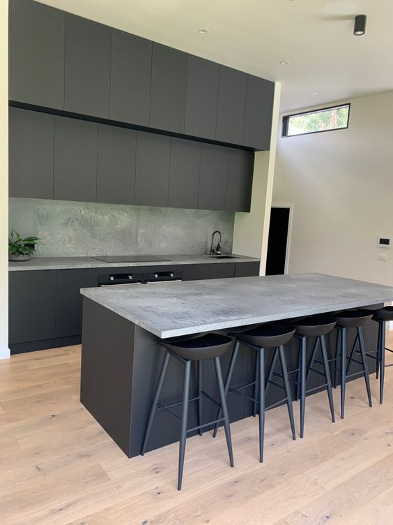 This is an example of a mid-sized contemporary galley kitchen in Melbourne with flat-panel cabinets, black cabinets, quartz benchtops, grey splashback, engineered quartz splashback, black appliances, with island and grey benchtop.