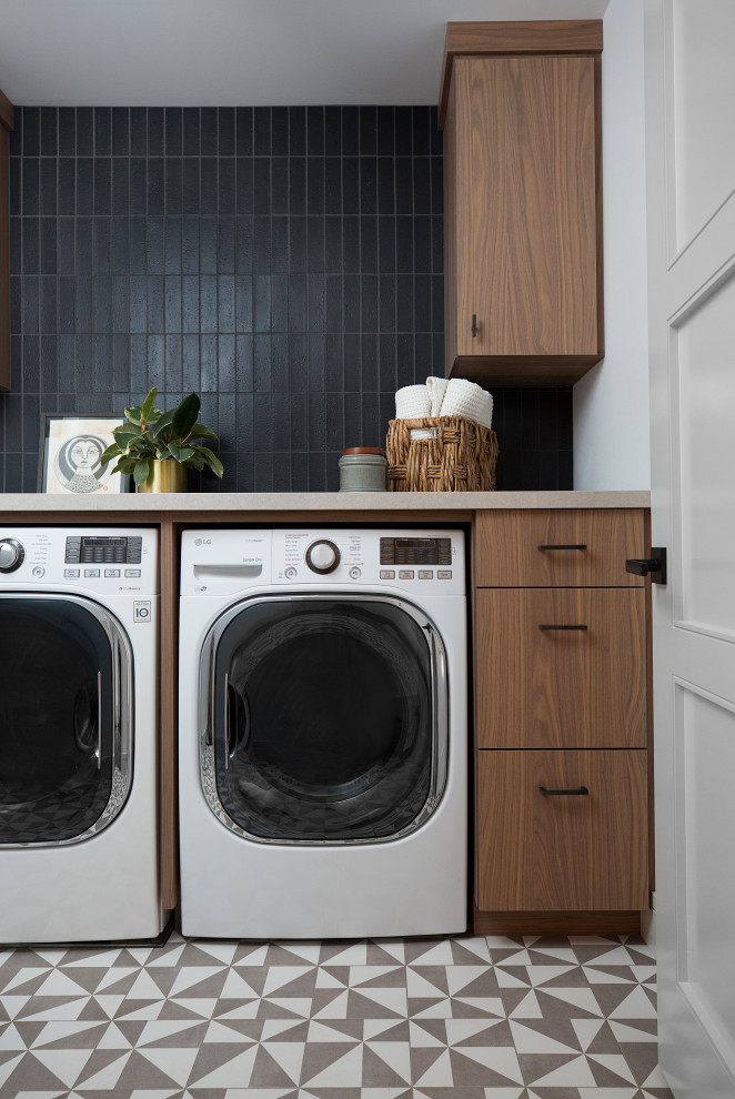 Mid-sized contemporary single-wall dedicated laundry room in San Francisco with flat-panel cabinets, medium wood cabinets, quartz benchtops, black splashback, brick splashback, white walls, porcelain floors, a side-by-side washer and dryer, multi-coloured floor and brown benchtop.