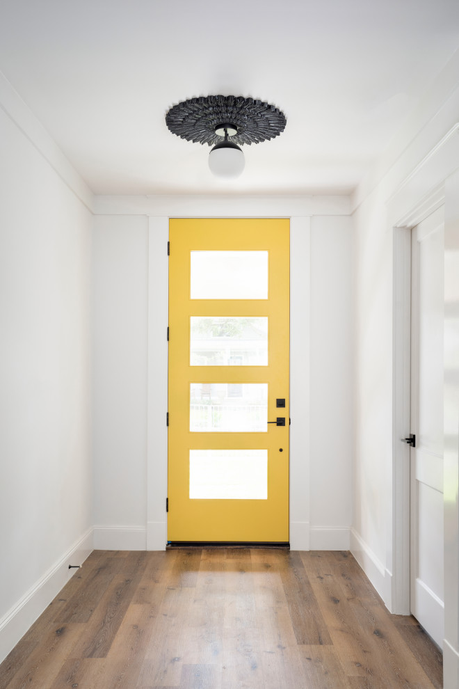 На фото: прихожая в стиле неоклассика (современная классика) с белыми стенами, полом из винила, одностворчатой входной дверью, желтой входной дверью и коричневым полом с