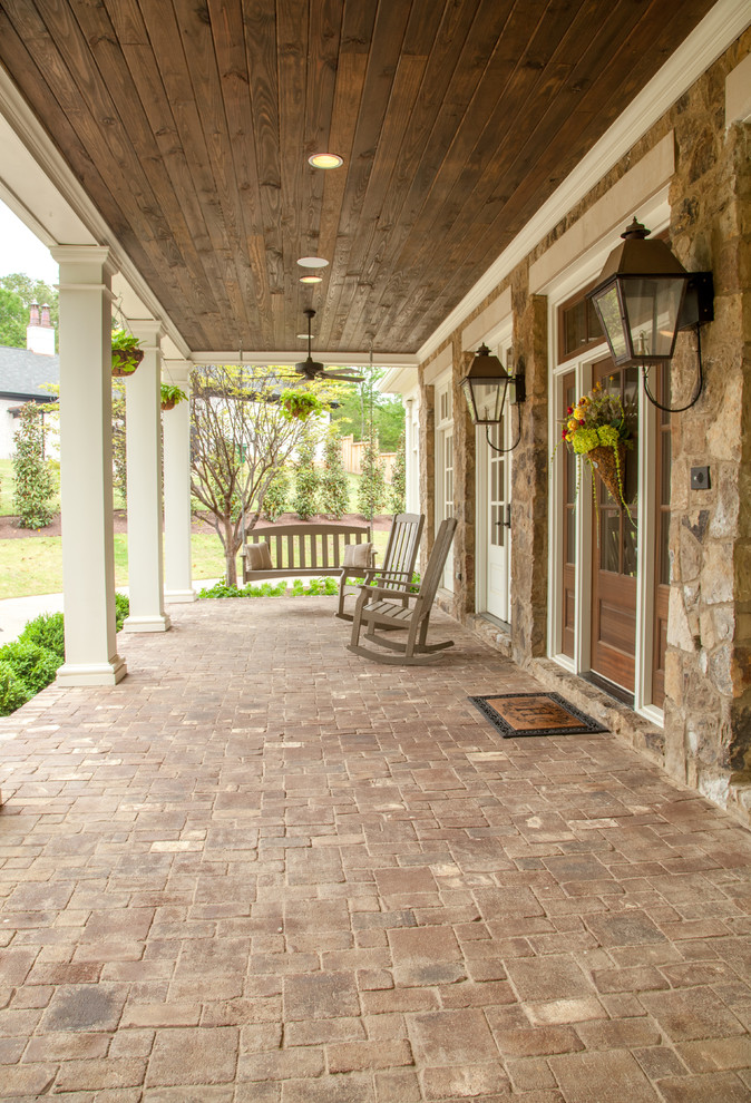 Design ideas for a mid-sized traditional front yard verandah in Nashville with brick pavers and a roof extension.