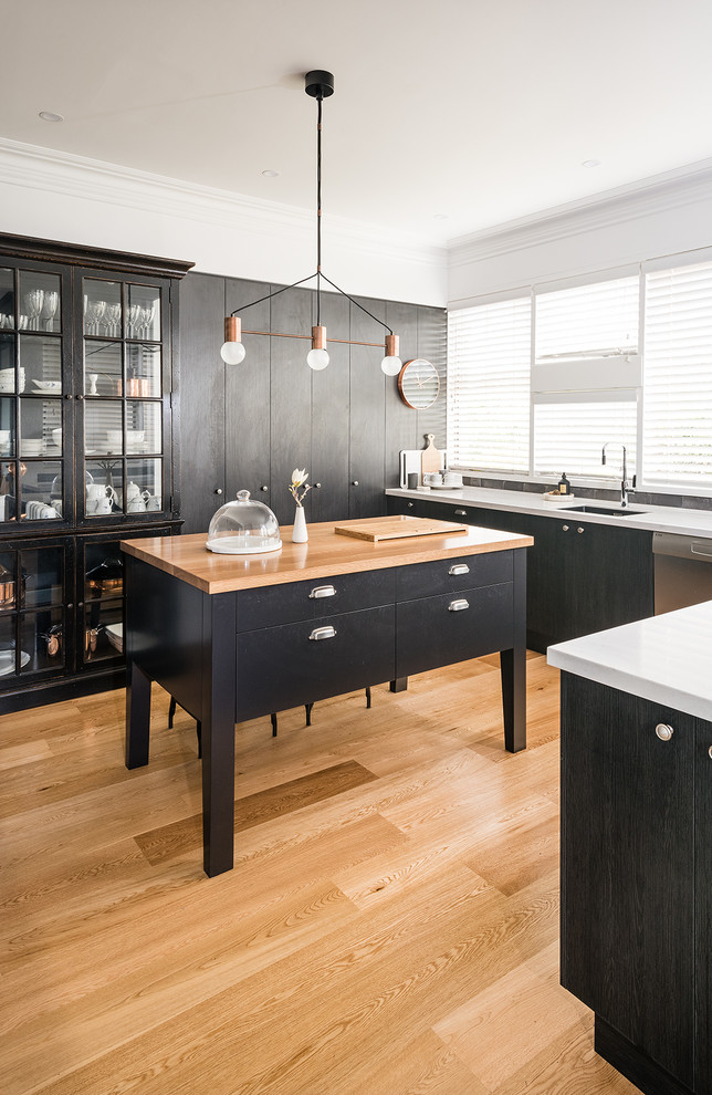 Photo of a large contemporary u-shaped open plan kitchen in Melbourne with an undermount sink, flat-panel cabinets, black cabinets, solid surface benchtops, grey splashback, with island, stainless steel appliances, ceramic splashback and light hardwood floors.
