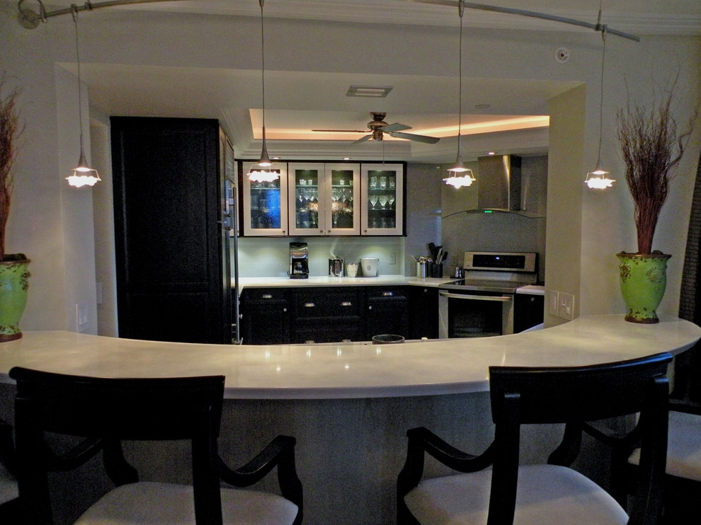 Example of a mid-sized trendy u-shaped medium tone wood floor eat-in kitchen design with a single-bowl sink, glass-front cabinets, brown cabinets, solid surface countertops, gray backsplash, porcelain backsplash and stainless steel appliances