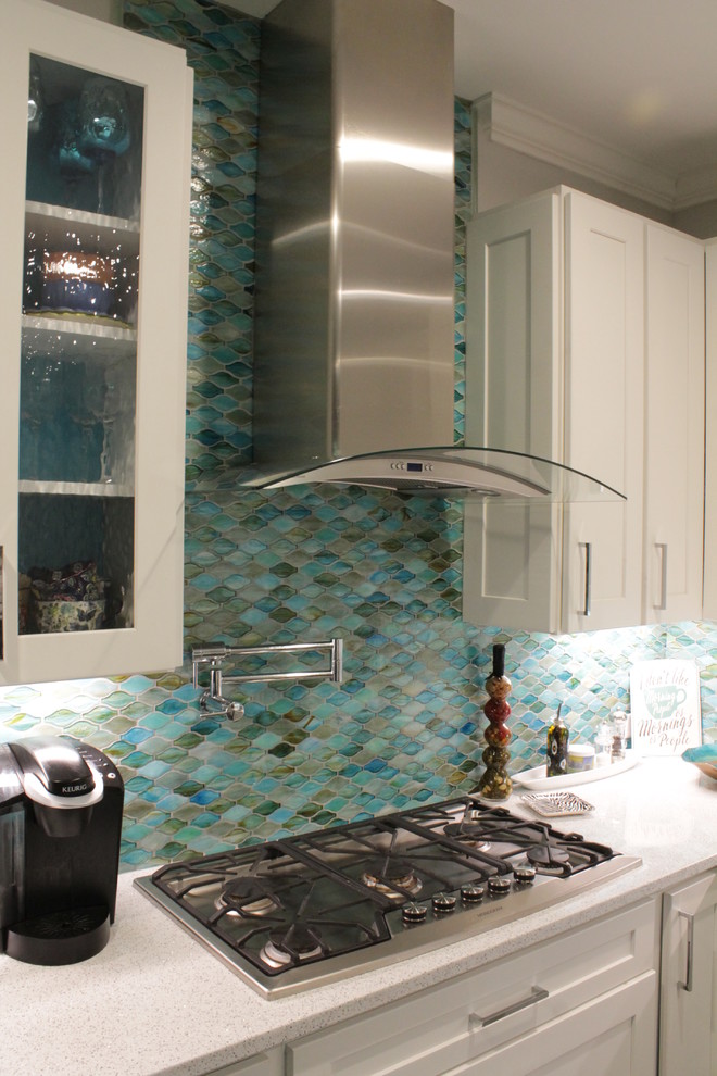 This is an example of a transitional eat-in kitchen in Other with an undermount sink, flat-panel cabinets, solid surface benchtops, blue splashback, glass tile splashback, stainless steel appliances, with island, white benchtop and white cabinets.