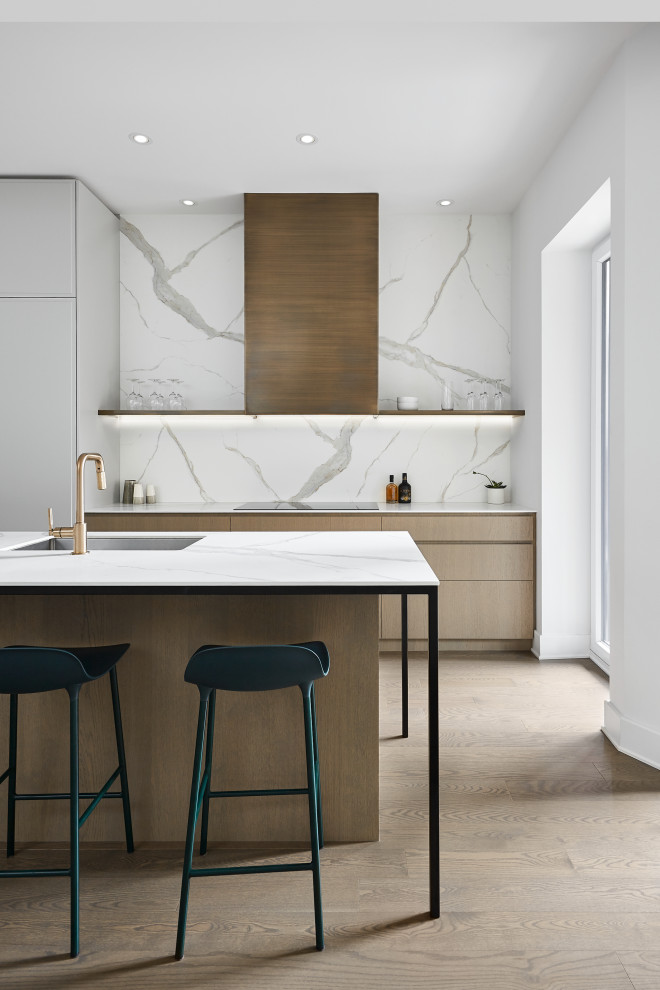 Mid-sized minimalist single-wall medium tone wood floor and brown floor eat-in kitchen photo in Montreal with an undermount sink, flat-panel cabinets, medium tone wood cabinets, quartz countertops, white backsplash, ceramic backsplash, paneled appliances, an island and white countertops