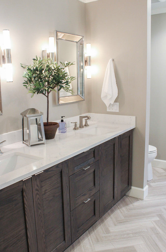 Inspiration for a large transitional master limestone tile limestone floor and beige floor freestanding bathtub remodel in Denver with brown cabinets, quartz countertops, a hinged shower door, shaker cabinets, gray walls and an undermount sink