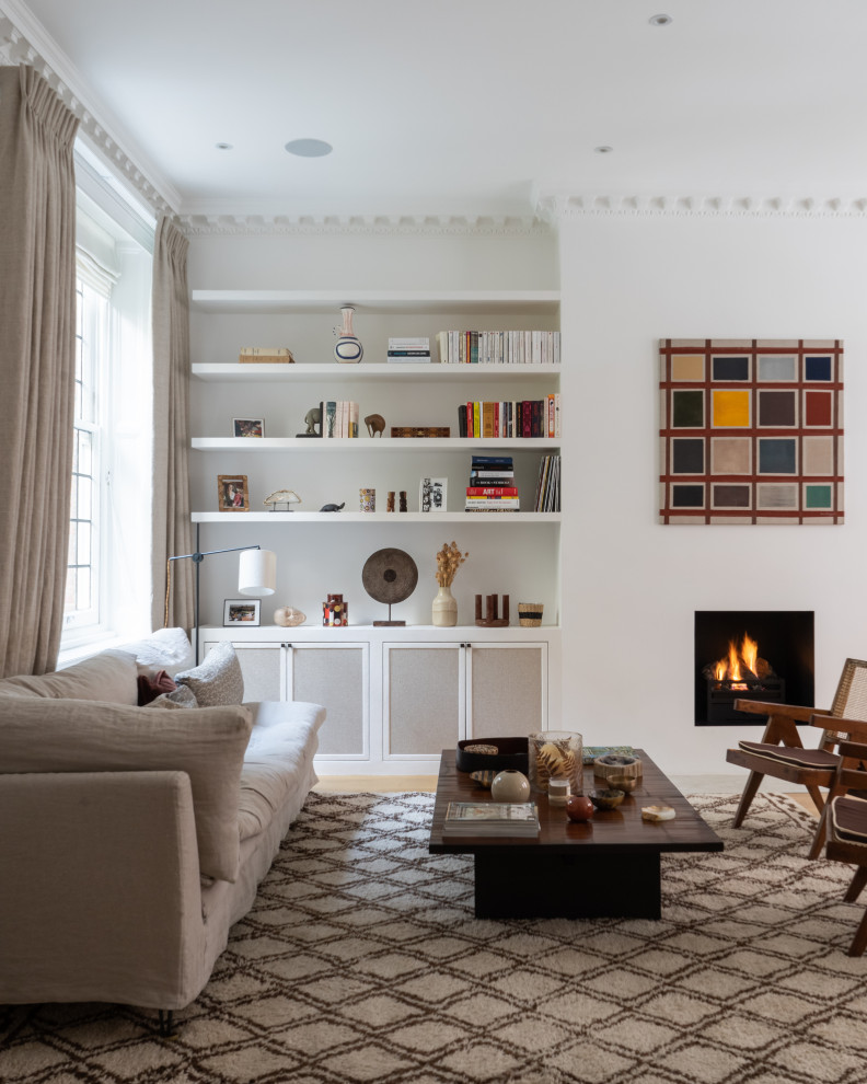 Inspiration for a traditional formal enclosed living room in London with white walls, light hardwood flooring, a standard fireplace, no tv and beige floors.
