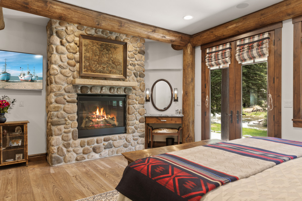 Example of a mid-sized mountain style guest bedroom design with a standard fireplace and a stone fireplace