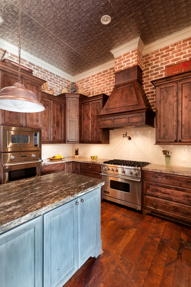 Example of a large mountain style u-shaped medium tone wood floor open concept kitchen design in Houston with a farmhouse sink, furniture-like cabinets, medium tone wood cabinets, granite countertops, white backsplash, subway tile backsplash, stainless steel appliances and an island
